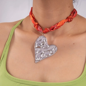 Dettaglio del ciondolo a cuore martellato argento su collana foulard in seta arancione