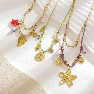 Vue détaillée de colliers tressés colorés avec pendentifs dorés boho et perles sur support blanc
