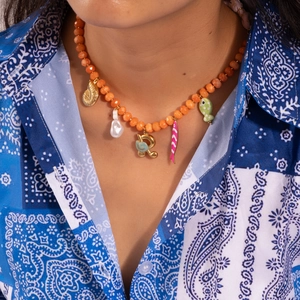 Detail of beaded necklace with orange beads, gold charms, pearl and colorful fish pendants