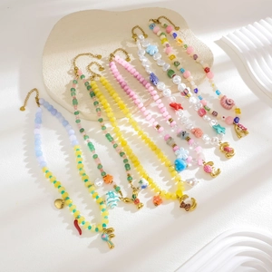 Close-up of colorful beaded necklaces with ocean-themed pendants and gold lobster clasps