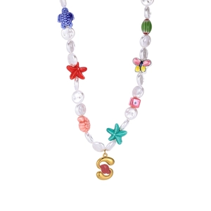 Detail of beaded pearl necklace with colorful sea charms and gold letter S pendant