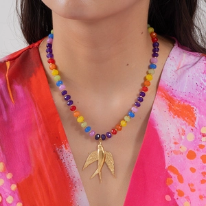 Gros plan d'un collier de perles multicolores avec un pendentif hirondelle dorée