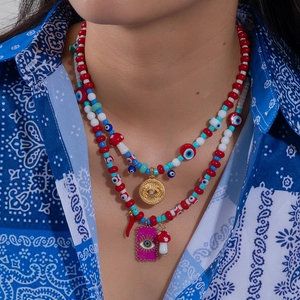 Macro detail of layered beaded necklace with evil eye charm and colorful beads