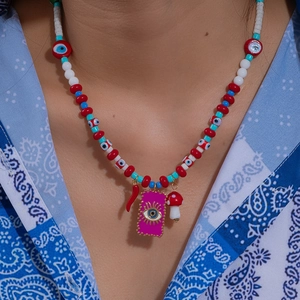 Bohemian beaded necklace with chili eye and mushroom charms on a blue patterned shirt