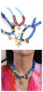 Detail view of Bohemian seashell star and evil eye charms on a colorful fabric scarf necklace