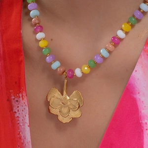 Collier en perles multicolores avec pendentif fleur dorée porté par un mannequin