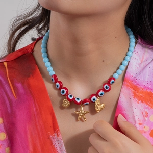 Blue beaded necklace with evil eye details and gold starfish pendants on a model