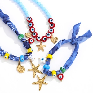 Detail of boho silk scarf necklace with colorful evil eye beads and starfish gold pendants