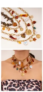 Detail of layered gold chain necklace featuring leopard heart and baroque pearl charms