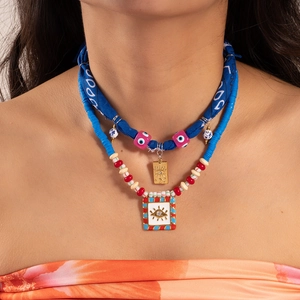 Detail of bohemian layered necklaces with evil eye charms and colorful beads for women