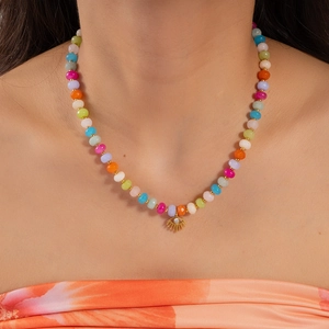 Close-up of a colorful beaded necklace featuring a golden evil eye pendant with crystal