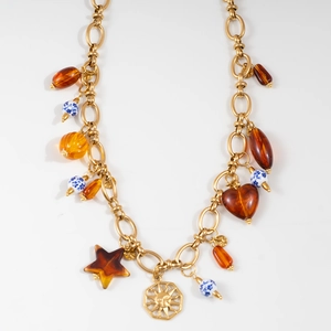 Detail of gold chain necklace with sun pendant, amber hearts, and ceramic beads