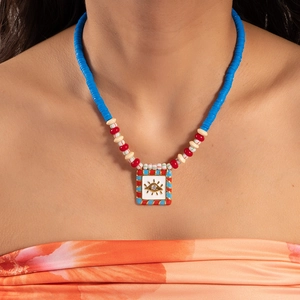 Detail of beaded evil eye pendant necklace with blue heishi beads for summer jewelry