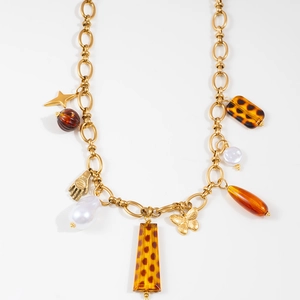 Close-up of golden stainless steel chain necklace with leopard charms and pearl details
