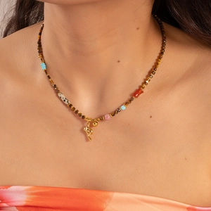 Macro detail of bohemian beaded necklace with tiger eye stones and golden mushroom charm