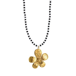 Detail of beaded necklace with black and white pearls and gold hammered flower pendant