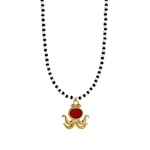 Detail of golden octopus pendant with red oval stone and black and white beaded chain