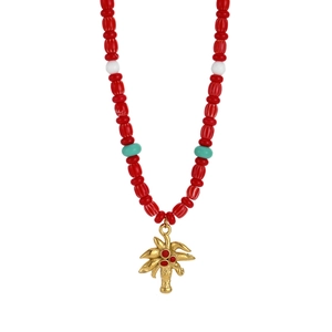 Detail showing a golden coconut tree pendant on a red beaded necklace for beach holidays