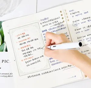 Gros plan détaillé d'un stylo blanc minimaliste écrivant sur un carnet de notes à spirales