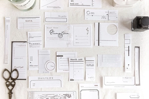 Flat lay of vintage scrapbooking paper set with decorative tags on white fabric