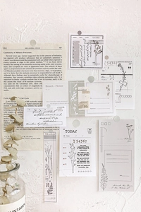 Detailed view of vintage aesthetic stationery paper collage pinned to a white textured wall