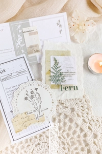 Macro detail of retro fern botanical stickers and vintage paper scraps on lace fabric