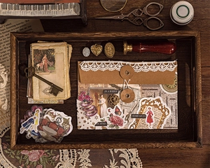 Close-up of vintage scrapbook kit with PET stickers and brass keys in a wooden tray