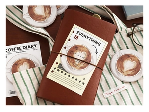 Detail of a vintage coffee diary leather notebook with decorative tags on a canvas bag