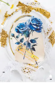 Close-up of large blue rose scrapbooking sticker with gold foil text in vintage frame