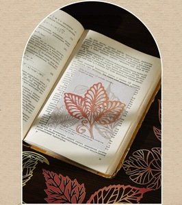 Detalle de marcapáginas de metal hueco con forma de hoja sobre un libro antiguo