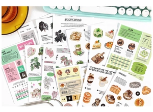Flat lay of diverse aesthetic planner stickers with plant and bakery themes on a cozy desk