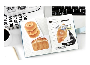 Macro detail of hand-painted bread theme scrapbooking stickers on a gridded notebook