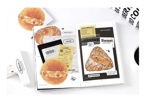 Detailed view of bread-themed vintage stickers and paper ephemera used in a journal diary