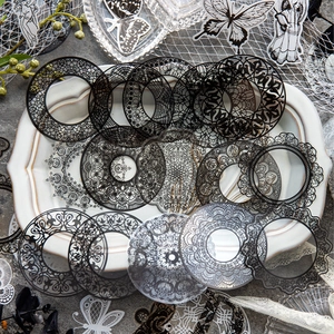 Vintage lace scrapbook stickers with black and white floral patterns on a ceramic plate