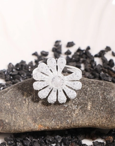 Macro shot of silver daisy ring with zircon petal inlay on natural brown stone base