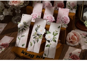 Macro shot of vintage style floral bookmarks with rose and camellia on a wood stand