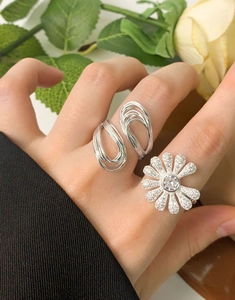 Close-up of S925 silver daisy ring with cubic zirconia and minimalist layered band on finger