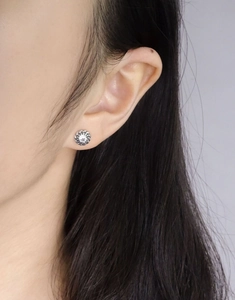 Close-up of S925 silver twist stud earrings with sparkling white cubic zirconia on ear