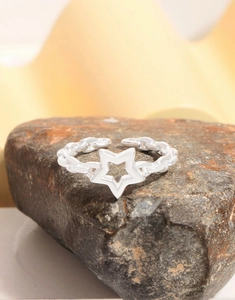 Macro shot of silver sterling star ring with chain texture on a dark textured rock surface