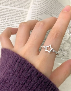 Detailed view of an S925 sterling silver star ring on a finger with a cozy lifestyle background