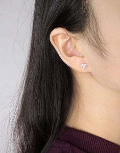 Gros plan d'une boucle d'oreille en cœur en argent S925 avec zircon sur l'oreille