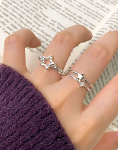Detailed view of S925 sterling silver star chain rings worn on a hand with a book background