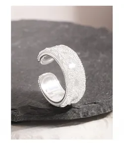 Macro shot of silver S925 sterling silver ring with woven lace texture and open band design