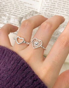 Detail of stacked S925 silver heart rings with radial patterns and beaded texture