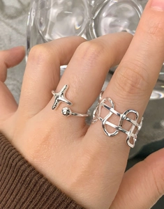 Detail view of irregular woven hollow ring and star design in polished silver finish