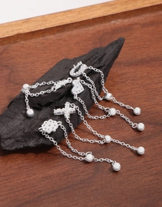 Detailed view of S925 sterling silver tassels with floral and heart charms on wood
