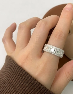 Detailed view of silver woven lattice ring with beaded edges worn on index finger