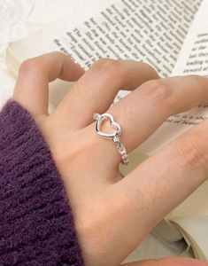 Detail of silver S925 heart ring with chain texture worn with a purple sweater