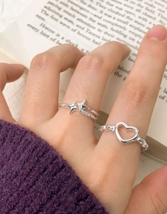 Detail of silver S925 sterling silver heart and star rings set on a purple sweater