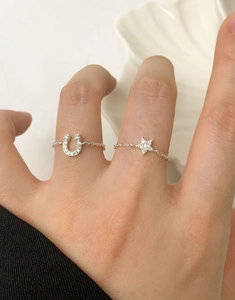Detail of adjustable silver chain rings featuring horseshoe and star-shaped crystal charms